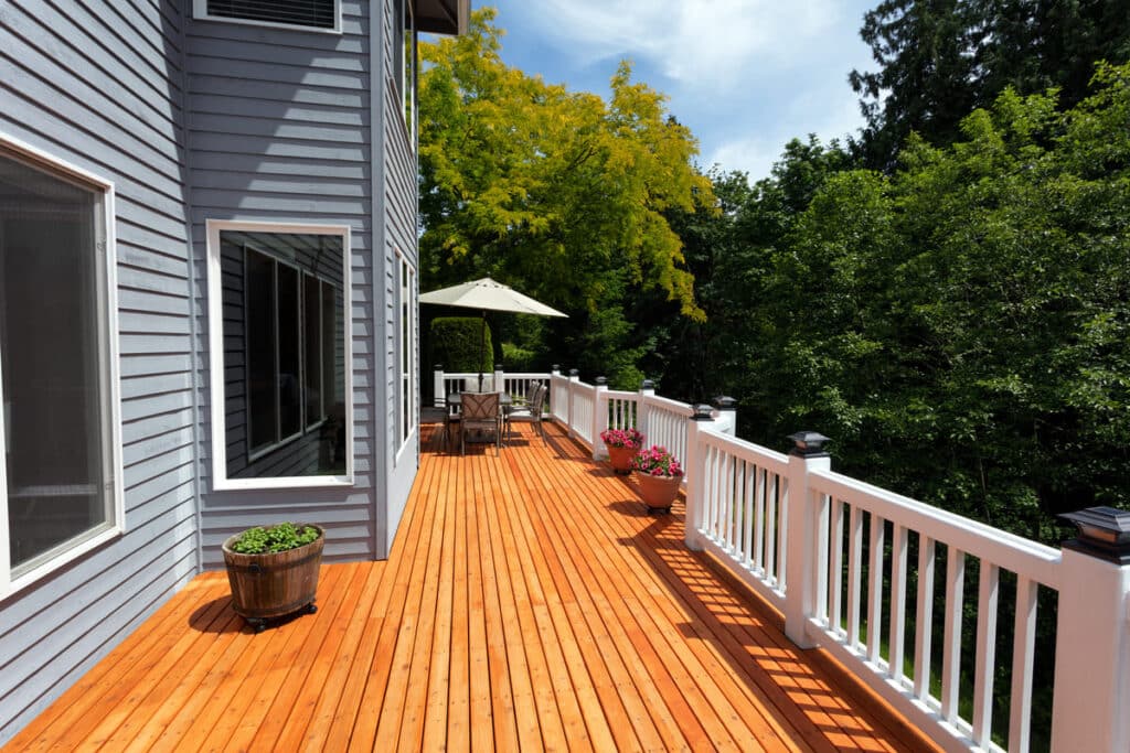 spacious wooden deck with white railings and outdoor seating